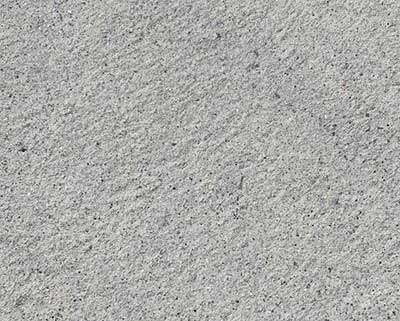 Close-up of sandblasting cleaning a concrete wall surface.